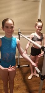 Two girls using a ballet barre to practice at home